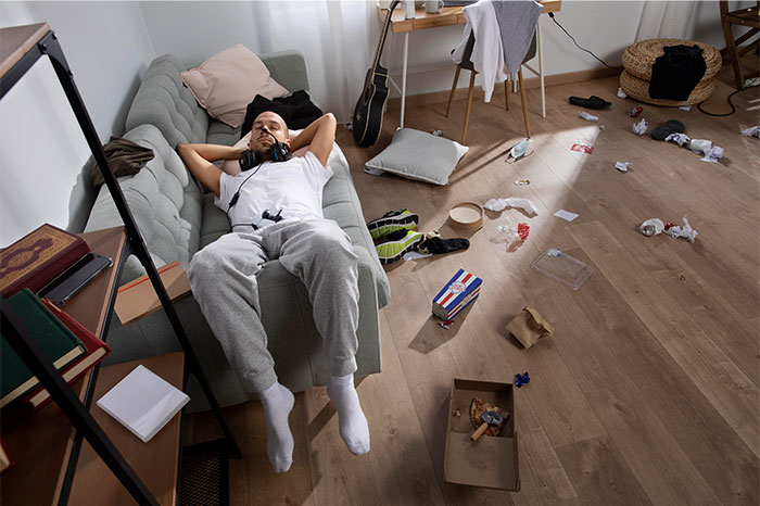 Man lying on couch in messy room with trash on floor, illustrating moments when people decided to stop helping others out - 33