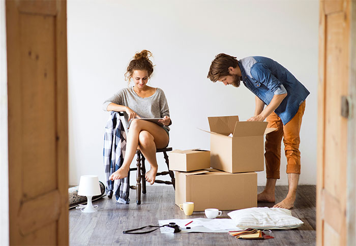 Couple packing boxes in a room, with one person sitting and the other organizing, illustrating moments people stop helping others. - 11