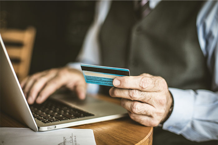 Man holding credit card and using laptop, illustrating moments when people decided to stop helping others out. - 5