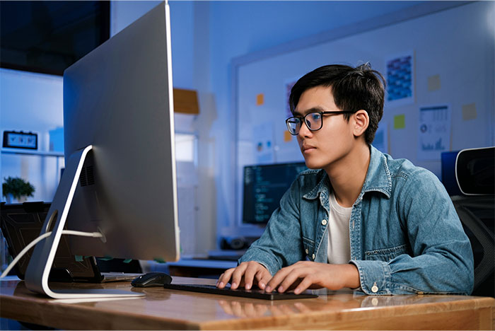 Young man focused on computer screen, working late in office, representing times people decided to stop helping others out - 21