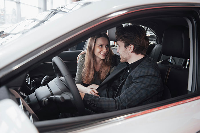 A young couple sitting inside a car, smiling and sharing a moment, illustrating times people decided to stop helping. - 51
