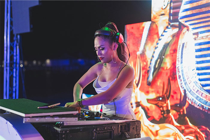 Woman DJ wearing headphones, focused on mixing music at an outdoor event, illustrating times people stopped helping others. - 47