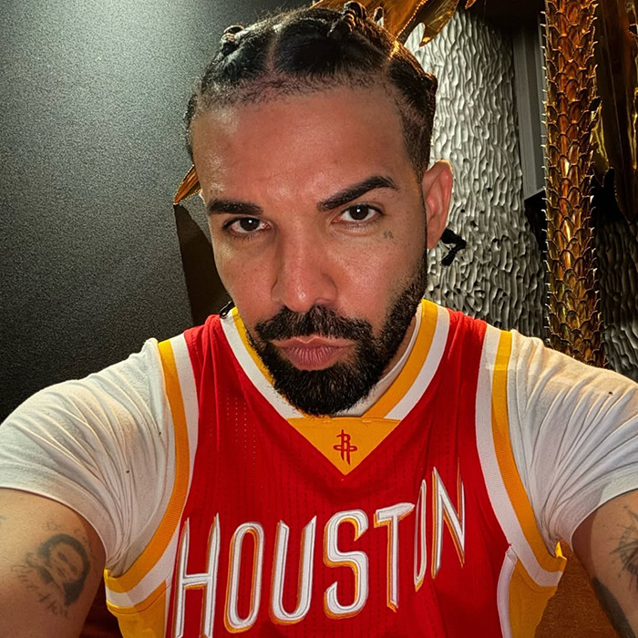 Drake taking a close-up selfie indoors wearing a Houston basketball jersey amid plastic surgery abs rumors.