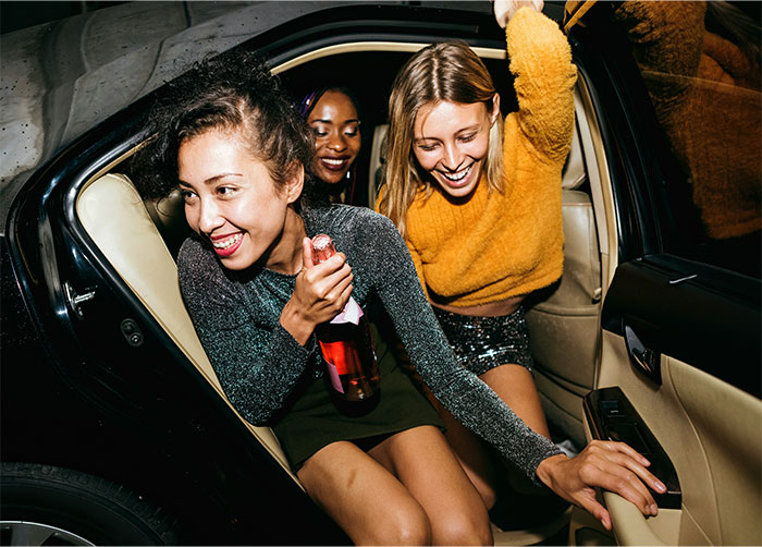 Three women having fun inside a car, with one holding a bottle, capturing a drunk wife moment in social setting. - 26