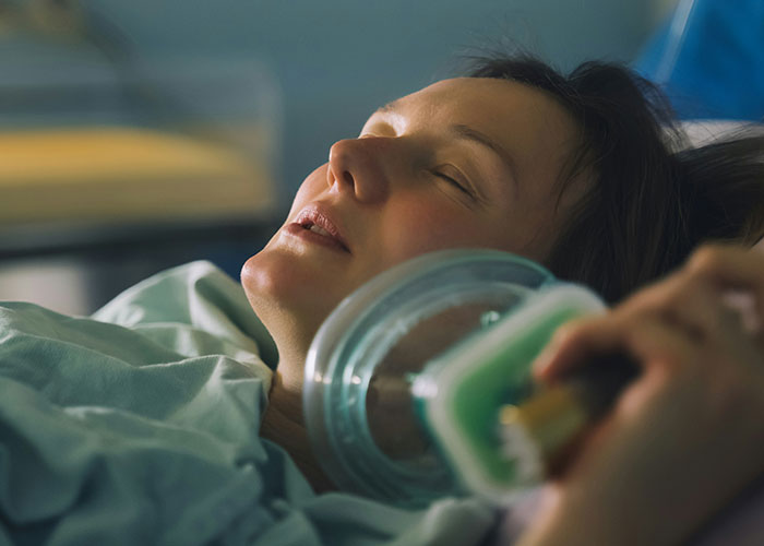 Woman resting in hospital bed with oxygen mask, representing dangers from dumb reasons that almost cost lives.