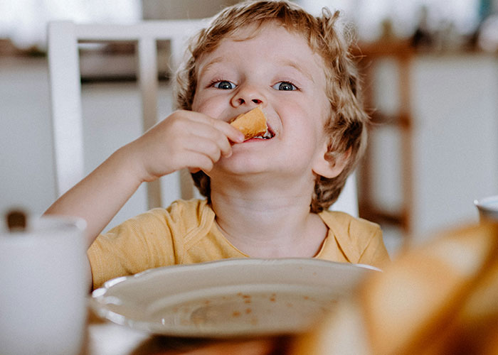 Young child eating food at the table, illustrating one of the dumbest reasons that almost cost people their lives.
