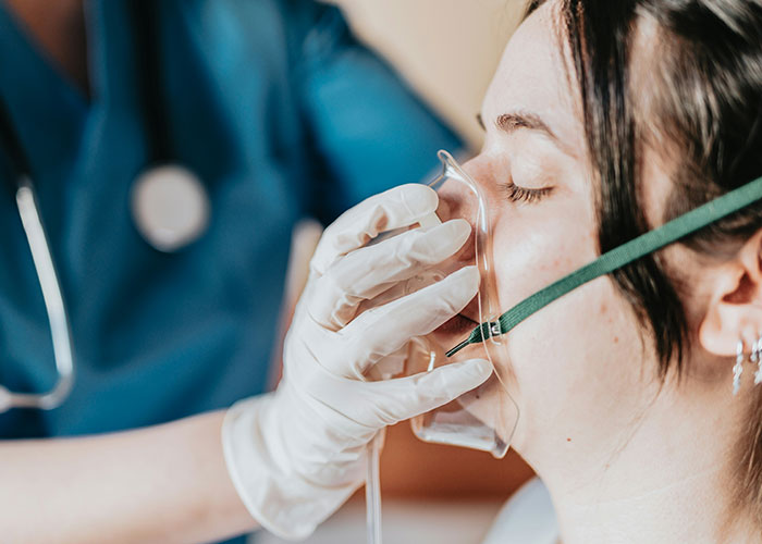 Woman receiving oxygen mask from medical professional, highlighting dumbest reasons that almost cost people their lives