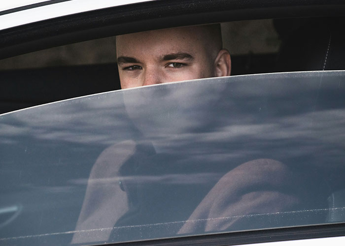Man looking through car window with a serious expression, illustrating dumbest reasons that almost cost lives.