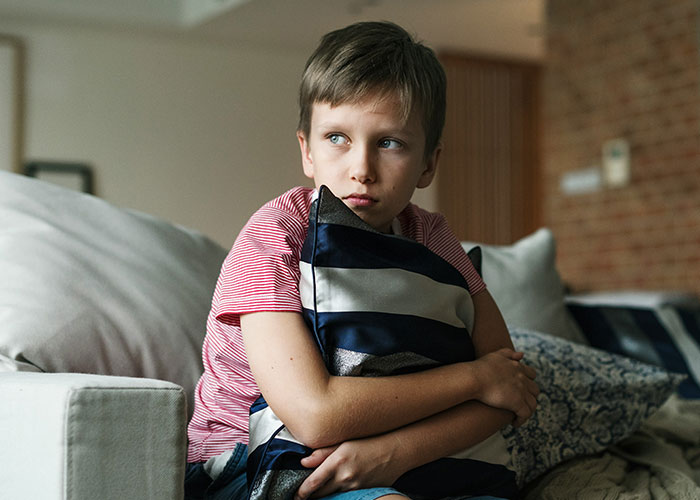 Young boy hugging a pillow with a worried expression, illustrating dumbest reasons that almost cost people their lives.