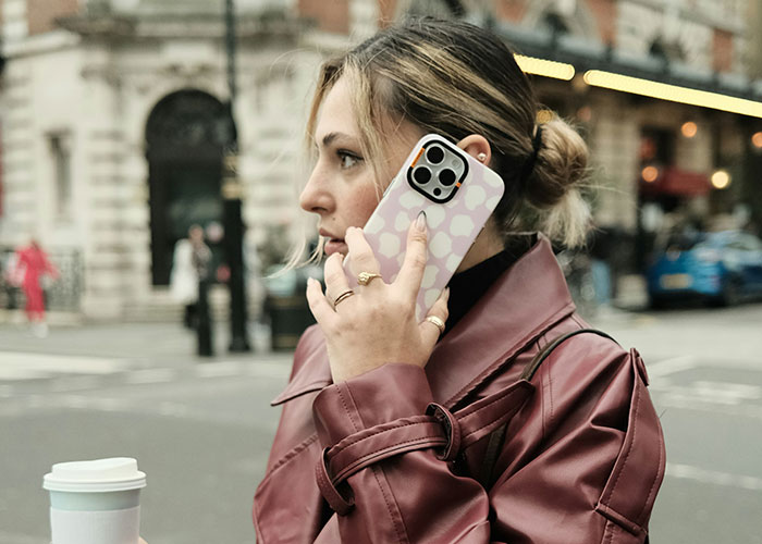 Young woman in a leather jacket talking on the phone on a city street, illustrating dumbest reasons that almost cost lives