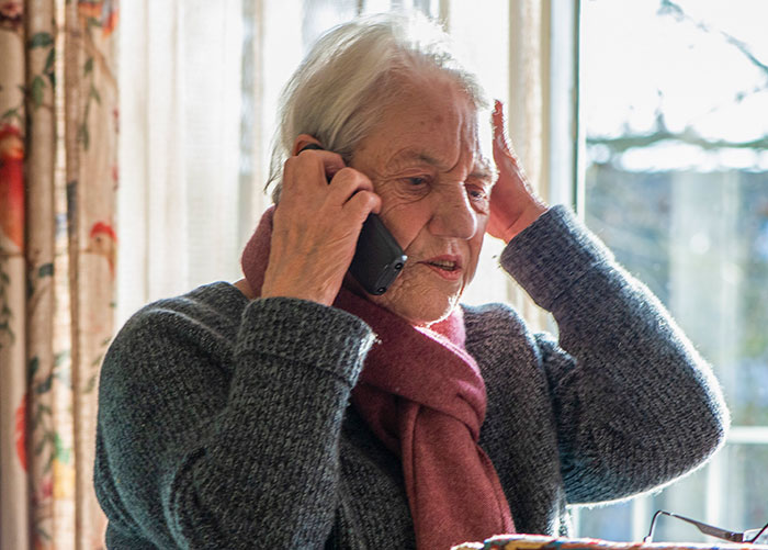 Elderly woman making a dramatic deathbed confession while talking on the phone in a cozy home setting. - 24