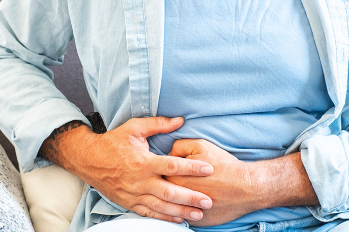 Person holding stomach while sitting down, illustrating dramatic deathbed confessions without actual death occurrences. - 21