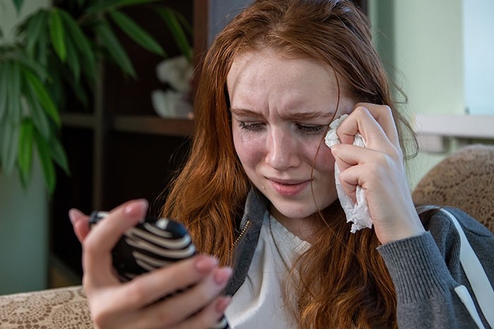 Young woman crying and wiping tears while holding a phone, illustrating dramatic deathbed confessions moments. - 10
