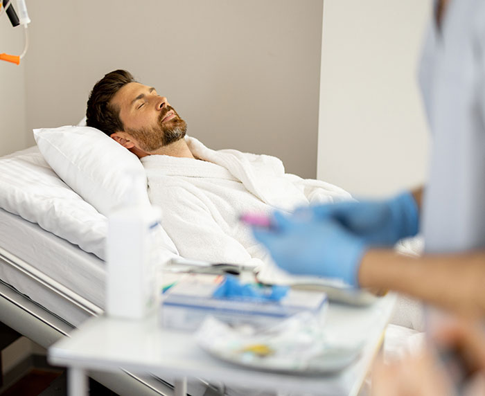 Man resting in a hospital bed wearing a white robe, symbolizing dramatic deathbed confessions without actually dying. - 14