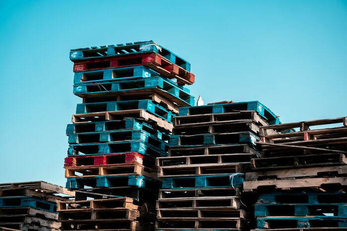 Stacks of wooden pallets under clear blue sky representing arrogant people’s regret moments in conflict discussions.