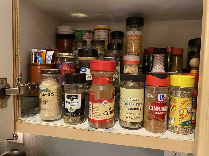 Spice jars neatly organized in a kitchen cabinet, illustrating a common roommate storage solution from Reddit tales.