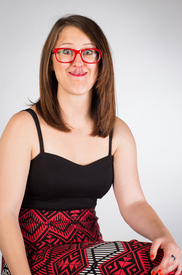 Woman with red glasses and patterned skirt making a silly face, illustrating easiest world records to break with time on hand.