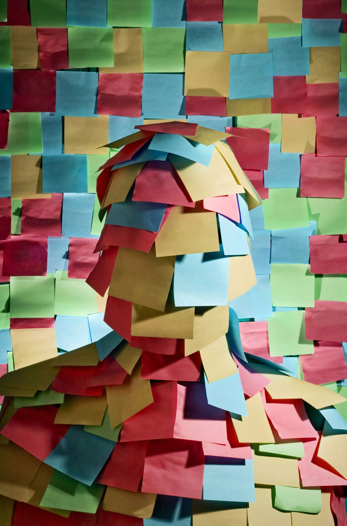 Person covered in colorful sticky notes against a wall full of sticky notes, representing easiest world records to break.