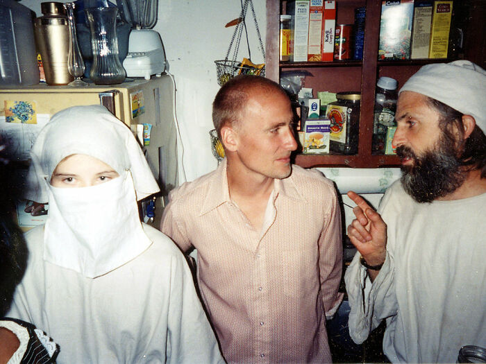 Three people in a kitchen setting, one wearing a white veil, depicting a scene with terrifying and horrific backstories. - 15