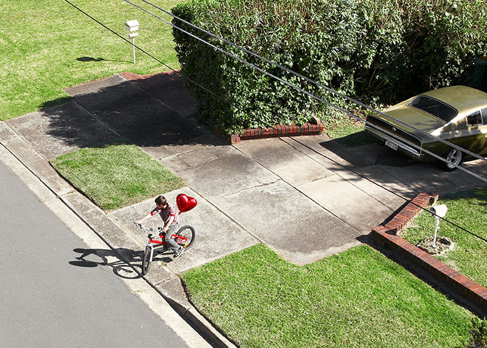 Child riding a bike on neighbor&rsquo;s driveway, highlighting parents treating it like their own backyard, homeowner frustrated.