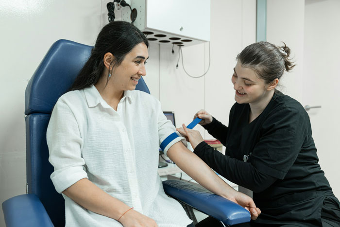 Woman preparing for plasma donation, medical staff applying tourniquet, highlighting plasma donation and staff interaction Woman preparing for plasma donation, medical staff applying tourniquet, highlighting plasma donation and staff interaction