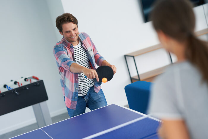 Young escape room employees playing table tennis, enjoying a break and team-building activities in a modern office space - 25