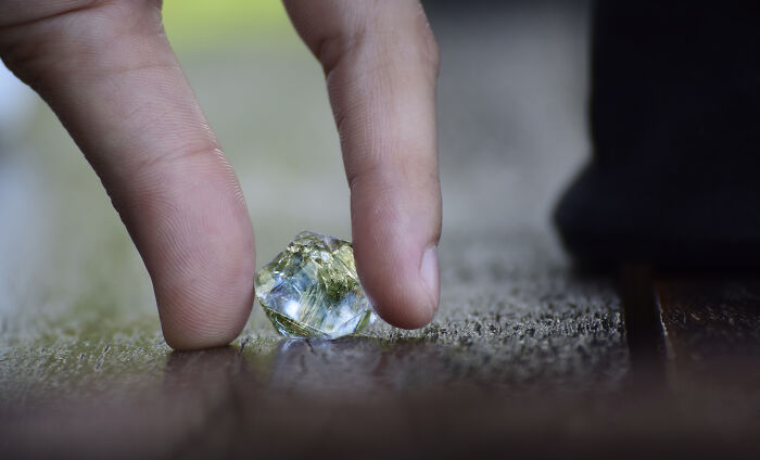 Close-up of hand picking up a crystal on the floor, illustrating escape room employees stories with detailed focus. - 12