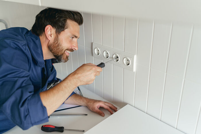 Escape room employees fixing electrical outlets with tools, focusing on maintenance and setup tasks indoors. - 5