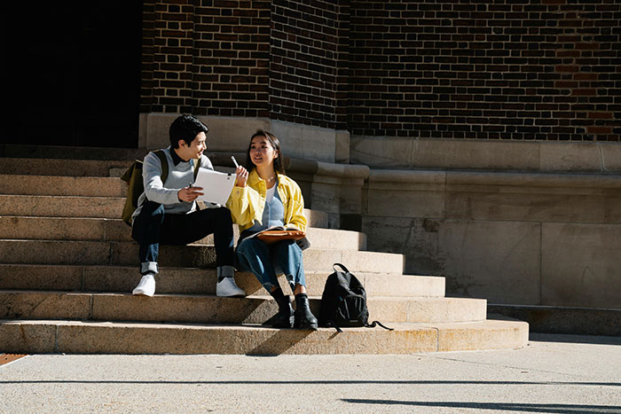 Woman and man meeting up on steps, discussing and sharing a tablet, representing co-parenting and secret child conversation. Woman and man meeting up on steps, discussing and sharing a tablet, representing co-parenting and secret child conversation.