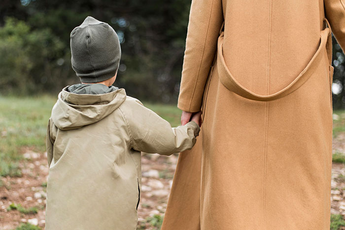 Child holding adult's hand outdoors, representing kids choosing to go no-contact after a dad destroys his marriage.