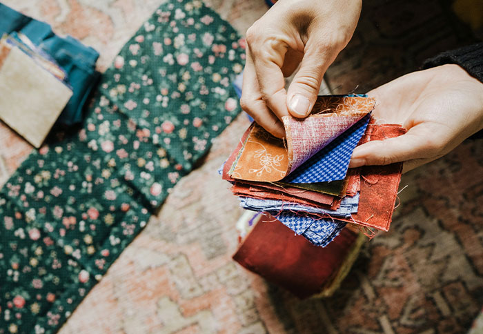 Hands holding colorful fabric squares for a personal and thoughtful gift project, evoking a sense of expensive craftsmanship.