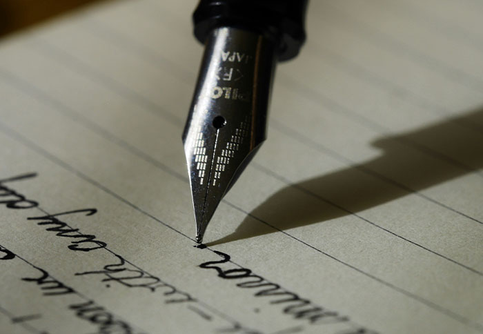 Close-up of a fountain pen writing on lined paper, illustrating personal and thoughtful gifts that feel expensive.