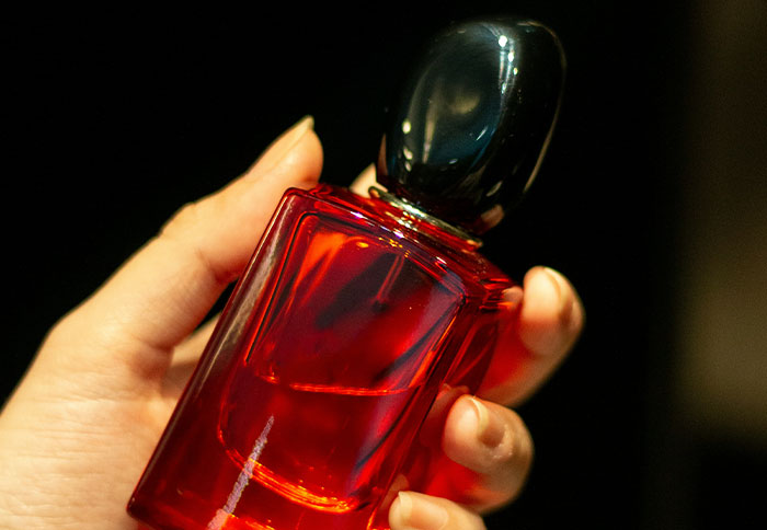 Hand holding a red perfume bottle, a personal and thoughtful gift that feels super expensive and special.