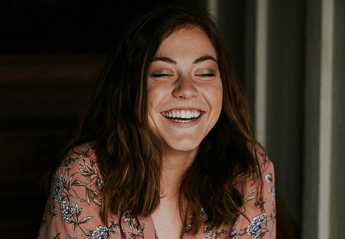 Young woman smiling warmly, wearing a floral blouse, embodying the joy of personal and thoughtful gifts that feel expensive