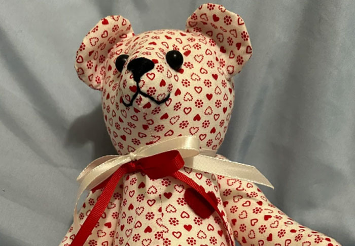 Fabric teddy bear with red heart patterns and ribbon, a personal and thoughtful gift idea that feels super expensive.