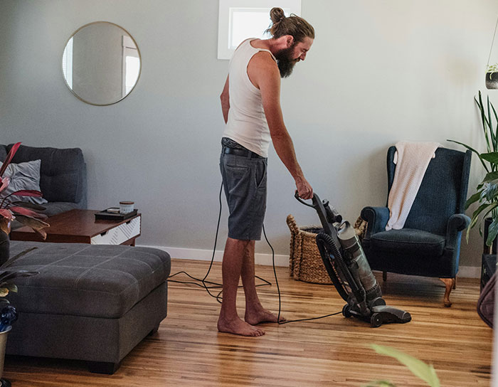 Man vacuuming hardwood floor in living room, representing personal and thoughtful gifts that felt expensive.