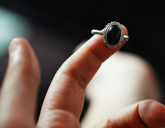 Hand holding a silver ring with a black stone, showcasing a personal and thoughtful gift that felt expensive.