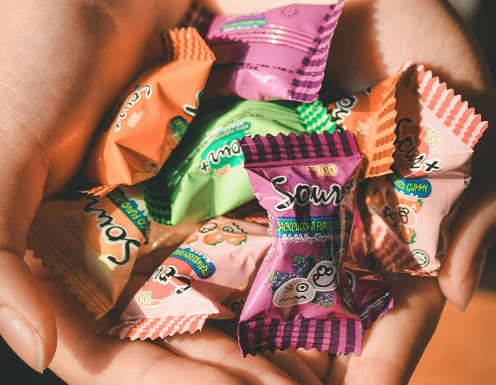 Close-up of hands holding colorful sour candy packages, a thoughtful gift idea that feels personal and expensive.