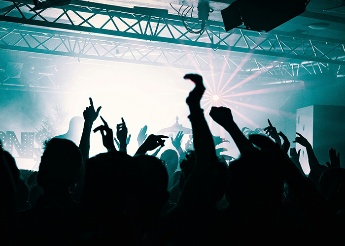 Crowd silhouetted with raised hands in front of bright stage lights, symbolizing doctors sharing crucial knowledge about death machines. - 9