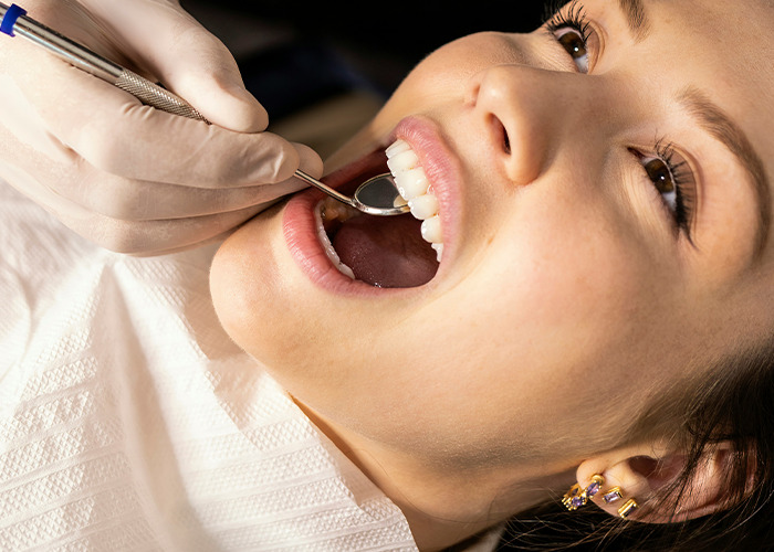 Close-up of a dentist using a dental mirror to examine the mouth of a patient at a medical clinic. - 34