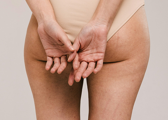 Close-up of a person’s hands behind their back showing natural skin texture and imperfections called death machines by doctors. - 13
