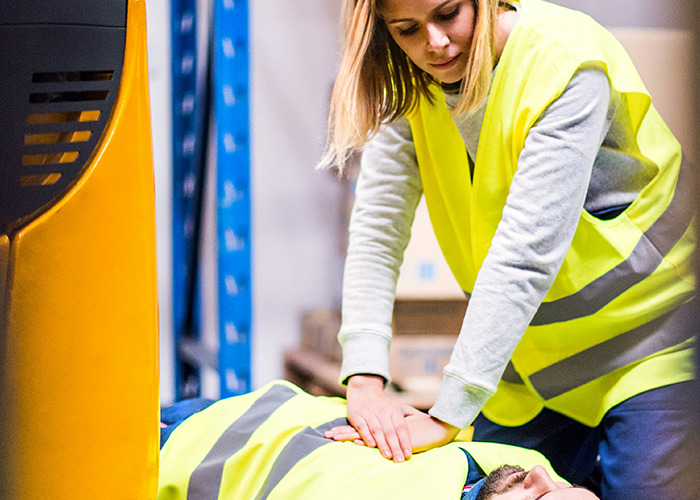 Woman performing CPR on a man in safety vests, highlighting doctors' warnings about death machines in the workplace. - 28