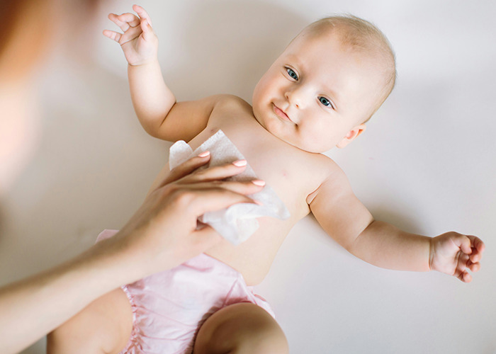 Baby lying down while an adult cleans their chest with a wipe, highlighting doctors' insights on health and care. - 32