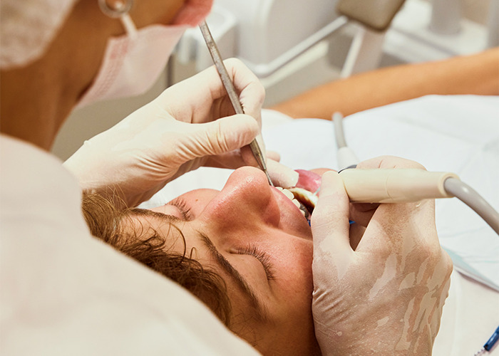 Dentist wearing gloves performing a dental cleaning on a male patient at a modern dental clinic. - 33