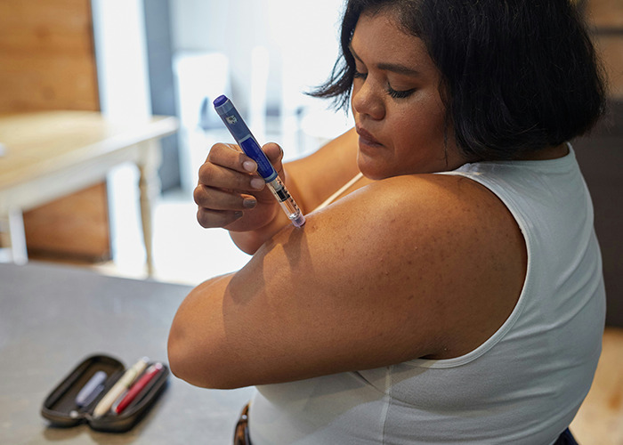 Woman injecting insulin into her arm, illustrating concerns doctors share about death machines like medical devices. - 37