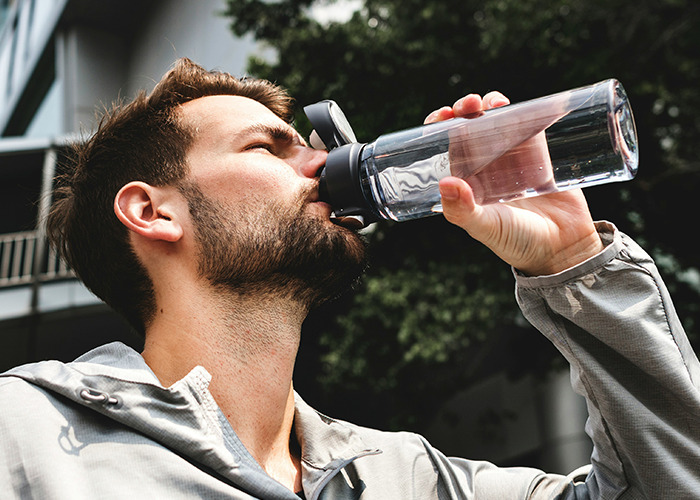 Man drinking water from a bottle outdoors, illustrating health awareness and doctors' advice on death machines risks. - 23