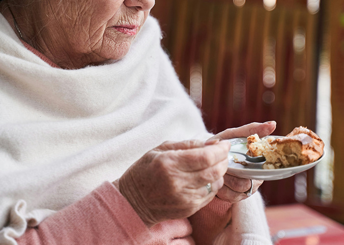Elderly woman wrapped in shawl eating dessert, highlighting health risks doctors warn about death machines. - 3