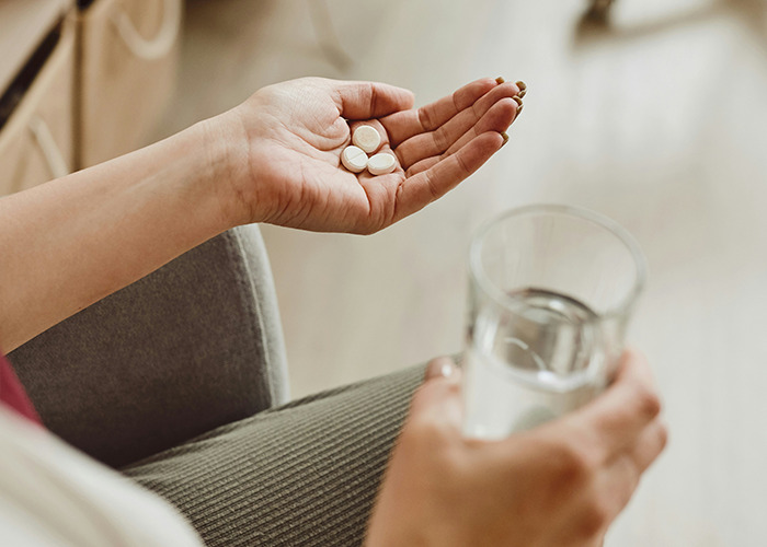 Hand holding pills and a glass of water highlighting doctors' warnings about death machines in healthcare settings. - 36