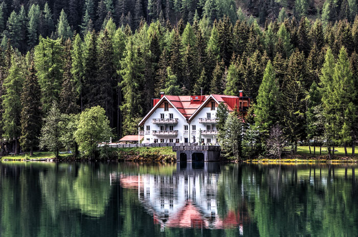 House with red roof reflected in lake near dense forest, symbolizing false accusation involving wife and father.
