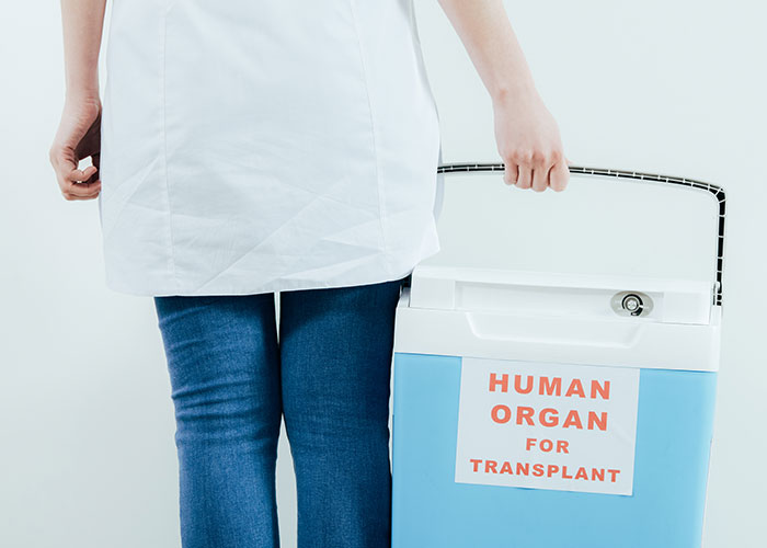 Medical professional holding a cooler labeled human organ for transplant, symbolizing organ donation refusal conflict.